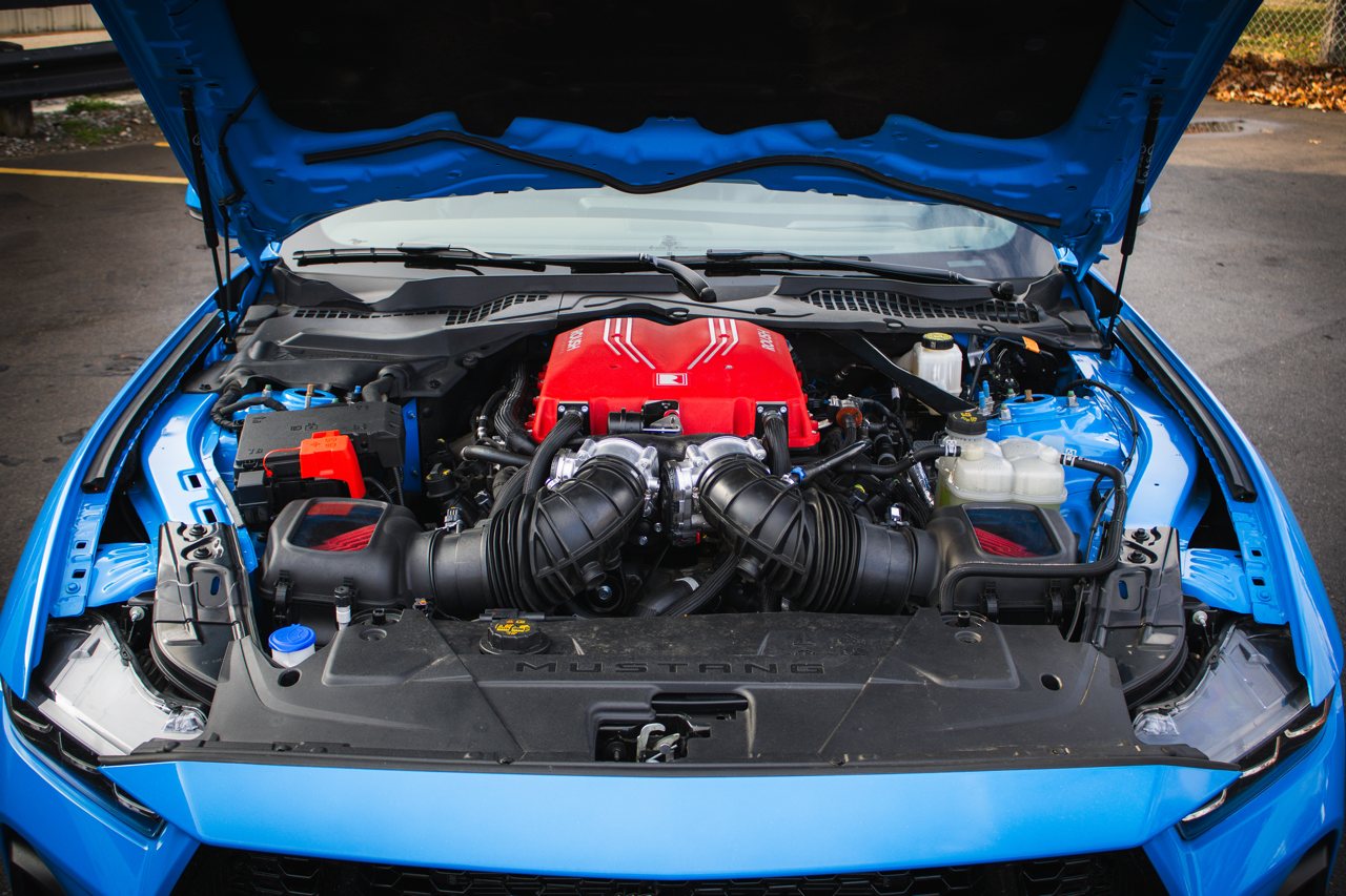 The 2026 Roush supercharger installed in a blue S650 Mustang engine bay, wide view.